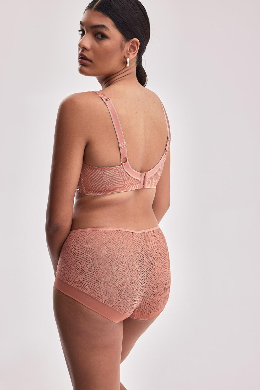 Modelka w biustonoszu miękkim Alles Celeste M i majtkach w kolorze brzoskwiniowym z ozdobnym wzorem